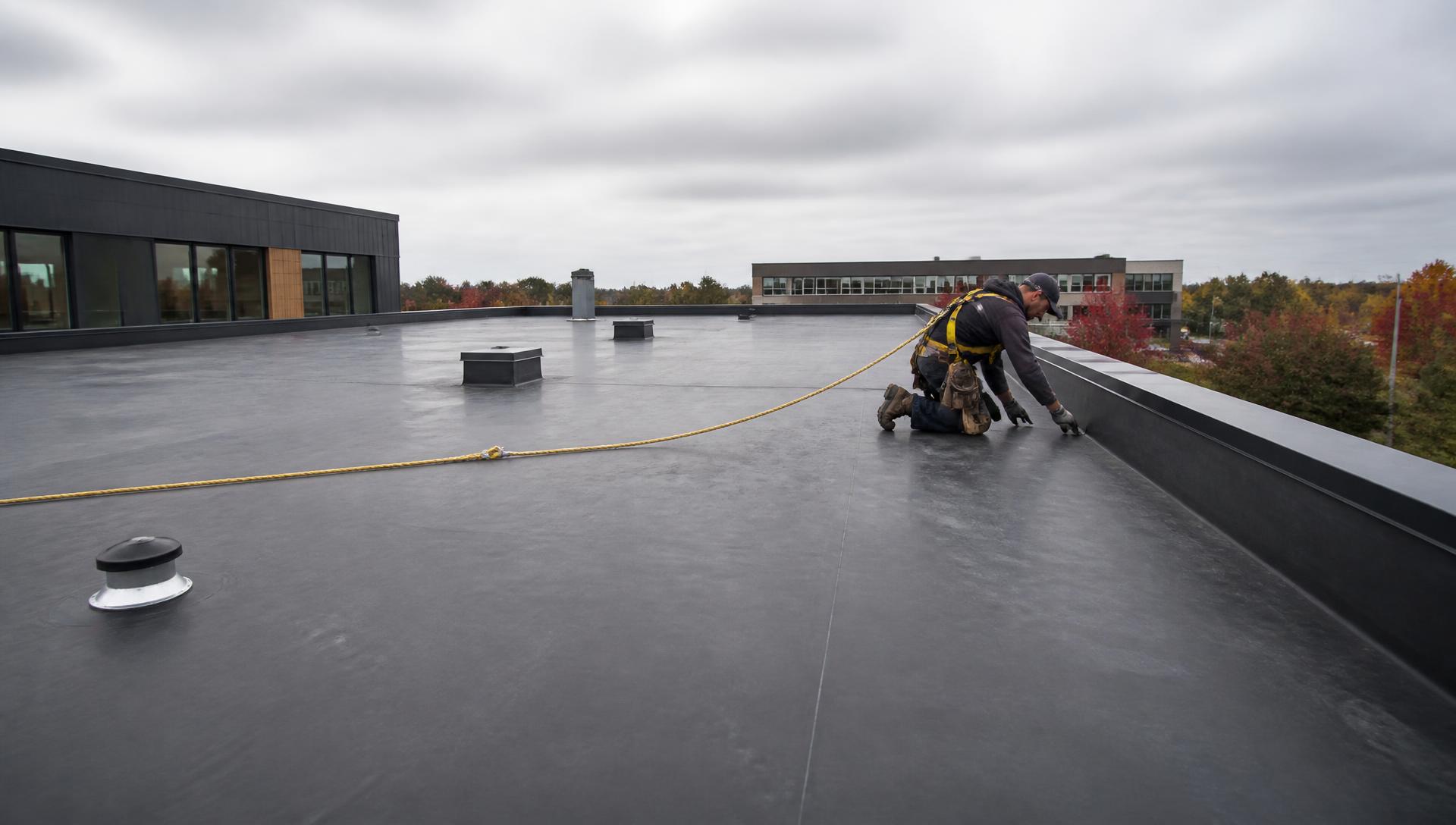 Dakdekker werkt aan een plat dak met EPDM-dakbedekking